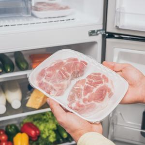 Photo of someone taking frozen meat out of the freezer to put into the refrigerator