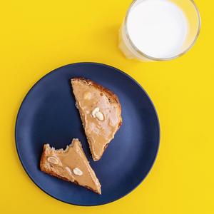 Photo of a plate with two slices of peanut butter toast and a glass of milk