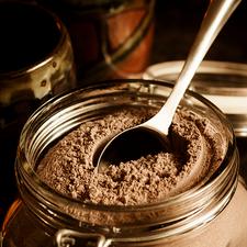 Photo of cocoa powder in a glass jar, with a spoon
