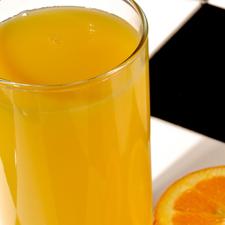 Photo of a glass of orange juice next to half an orange