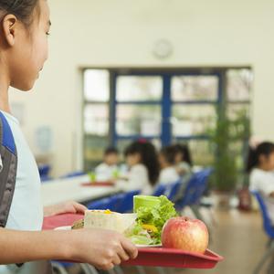 Girl carrying tray of food in school cafeteria
