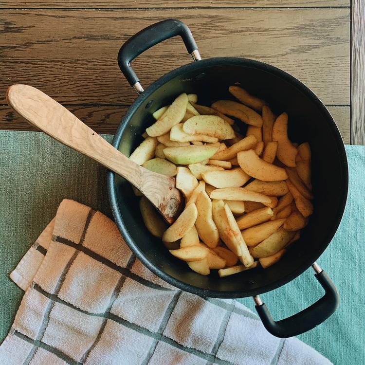 Photo of a cooking pot with sliced apples and a spoon