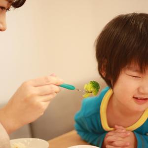 Photo of a child refusing food that mom is trying to feed