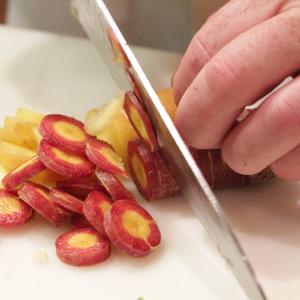 Photo of a person using a knife to cut vegetables