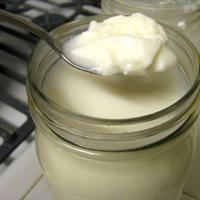 Photo of jar of yogurt, with a spoonful being presented on top