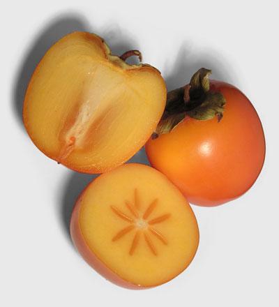 Photo of one whole persimmon and another one cut in half