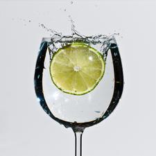 Photo of a slice of lime being splashed into a glass of water