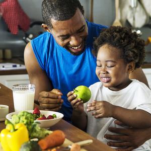 Photo of a man eating an apple with a small child